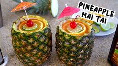 there are two pineapples with umbrellas on top of them and one has a drink in it