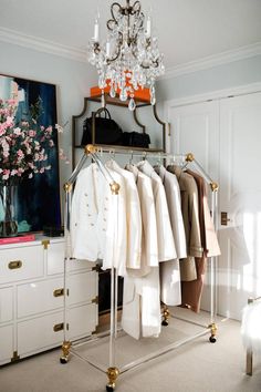 a closet with clothes hanging on racks and a chandelier in the corner next to it