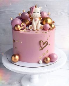 a pink cake with gold decorations and a unicorn figurine sitting on top of it