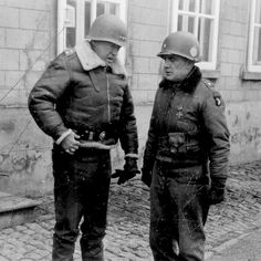 two men in uniforms standing next to each other on a cobblestone street with windows