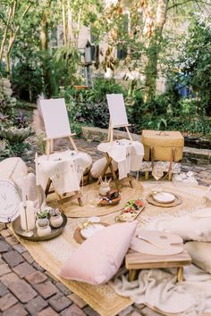 two empty chairs sitting on top of a rug next to pillows and other items in front of trees