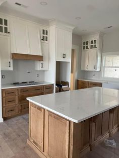 an empty kitchen with white cabinets and wood flooring in the center island, is shown