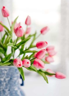 a blue vase filled with pink flowers on top of a table