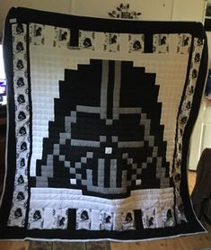 a black and white star wars themed quilt on a chair in front of a computer desk