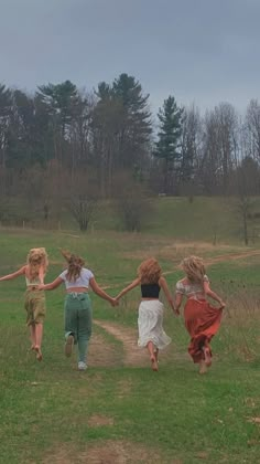 four girls running in a field holding hands