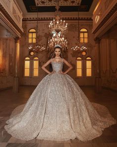 a woman in a wedding dress standing in a room with chandeliers on the ceiling