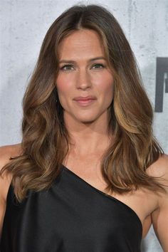 a woman with long hair wearing a black dress and looking off to the side at an event