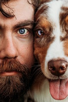 a man with blue eyes and a beard holds his dog's face close to the camera