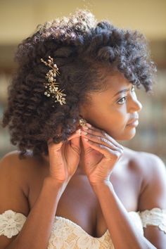 a woman with curly hair wearing a white dress and holding her hands to her face