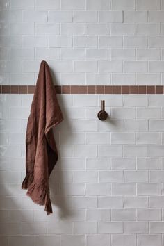 a brown towel hanging on a white brick wall