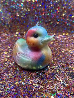 a small toy duck sitting on top of a pile of confetti sprinkles