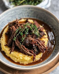 a bowl filled with meat and gravy on top of polenta grits