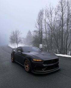 a black sports car driving down a road in the snow