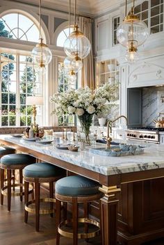 a large kitchen with marble counter tops and gold accents on the cabinets, along with bar stools