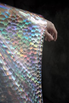 a person is holding up a holographic bag