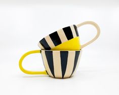 two striped coffee mugs sitting side by side on a white surface with one yellow and the other black