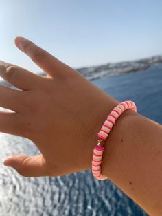 a person's hand with a pink and white beaded bracelet on the wrist