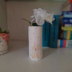 a white flower in a vase on a table next to some books and other items