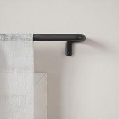 a curtain is hanging on the side of a wall with a black rod attached to it