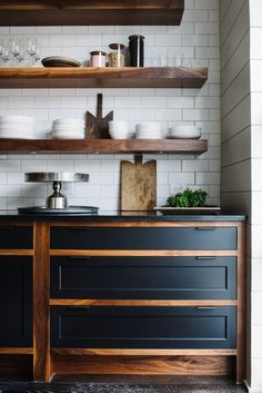 a kitchen with black cabinets and shelves filled with dishes