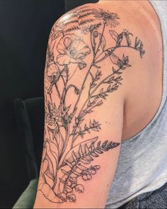 a woman's arm with flowers and leaves tattooed on the back of her shoulder