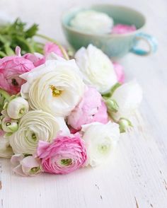 a bouquet of white and pink flowers next to a cup