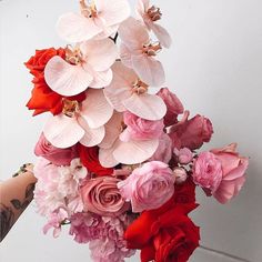 a woman holding a bouquet of pink and red flowers