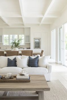 a living room filled with white furniture and lots of pillows on top of a wooden table