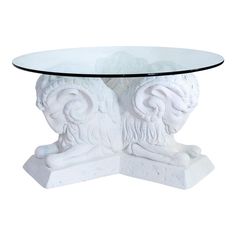 a glass table with two white lions on it's legs and an oval glass top