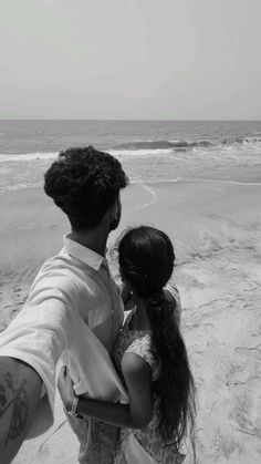 a man and woman are holding each other on the beach