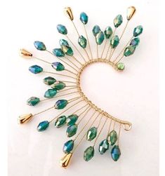 a brooch with green and gold beads on it's side, in the shape of a heart