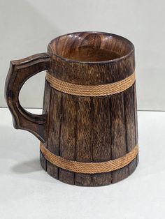 a wooden mug with rope wrapped around the bottom and sides on a white table top