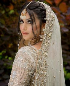 a woman wearing a bridal outfit and headpiece in the middle of her wedding day