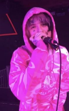 a man in a pink jacket singing into a microphone