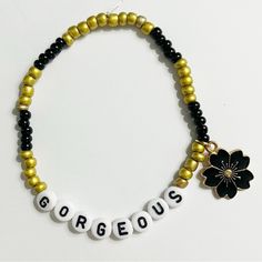 a black and gold beaded bracelet with a flower charm on it that says gorgeous