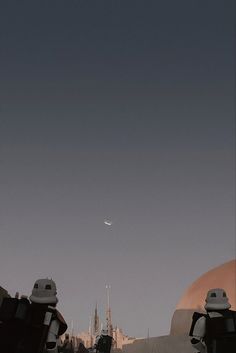 two robots are standing in front of a building and an airplane is flying over them