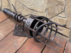 an old metal object sitting on top of a wooden table next to a stone wall