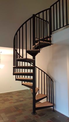 a spiral staircase in an empty room with tile flooring and white walls, leading to the second floor