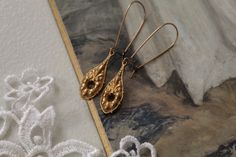 "Beautiful handmade Victorian Antique Georgian Barocco Rococo inspired antiqued gold plated brass filigree scroll dangle drop earrings. Mounted on an antiqued kidney hook ear wires. Measurements: approx. 2.5\" ✭ Shop more jewelry here ➜ https://www.etsy.com/shop/adriancompany?section_id=33299650 ✭ Adrian Company Vintage is partnering with The Veiled Ghost to offer handmade modern jewelry with Gothic Victorian Antique feel. ✭ All Veiled Ghost jewelry is nickel and lead free. ✭ All Veiled Ghost je Elegant Vintage Brass Earrings, Elegant Vintage Charm Brass Earrings, Elegant Brass Earrings With Vintage Charm, Elegant Brass Earrings With Antique Finish, Victorian Gold Earrings With Vintage Charm, Gothic Victorian, Vintage Ribbon, Handmade Modern, Victorian Gothic