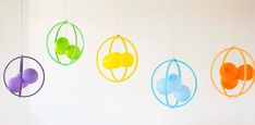 four colorful balls hanging from strings next to each other on a white wall in the shape of an egg