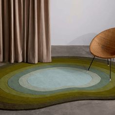 a round rug with an oval design on the floor in front of a curtained window