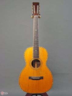 an old acoustic guitar is sitting on a stand