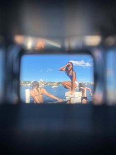 a reflection of two women in a mirror on the side of a boat at sea