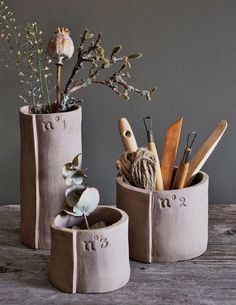 three cement pots with plants and scissors in them