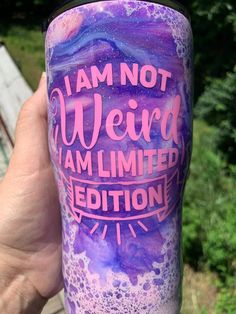 a hand holding up a purple and blue cup with writing on it that says i am not weird, i am limited edition