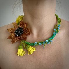 a woman wearing a yellow and green necklace with flowers on the back of her neck