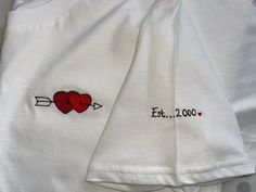 Valentine's couples gift embroidered T-Shirt organic cotton, mens and ladies sizes Help custom make a romantic T-shirt for yourself or a loved one or why not have matching Tees :)  Firstly choose the heart design you would like, please have a look at the images for options, next decide if you require any text for the sleeve. You may wish to have names, a date or a meaningful word/words. You can message me these details after the sale and I will create a free motion embroidered t-shirt just for you.  Free-motion embroidery means I can draw or trace any image using my sewing machine like a pen.  This gives me a lot of flexibility and I can tailor designs to suit your needs and requirements.  I currently only stock organic white cotton T-shirts but I can source additional colours such as navy White Family Matching T-shirt With Embroidered Text, Family Matching White T-shirt With Embroidered Text, White Embroidered T-shirt For Family Matching, White T-shirt With Embroidered Logo As Gift, White T-shirt With Embroidered Graphics As Gift, Couples Cotton T-shirt Gift, White Embroidered T-shirt For Gift, Couples Cotton T-shirt For Gift, White Embroidered T-shirt As Gift