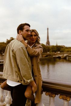 a man and woman standing next to each other on a bridge near the eiffel tower