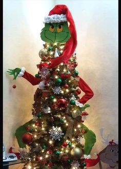 a christmas tree that has been decorated with lights and decorations, including an elf's hat