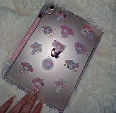 an apple laptop with hello kitty stickers on the front and side, sitting on a fluffy white surface